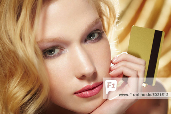 Nahaufnahme Porträt einer jungen Frau mit goldener Kreditkarte