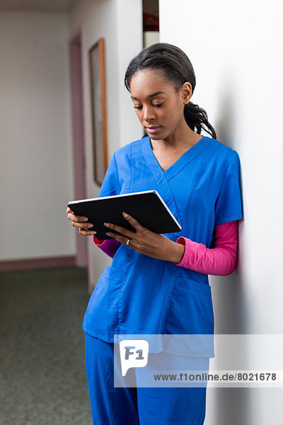 Krankenschwester mit digitalem Tablett im Krankenhausflur