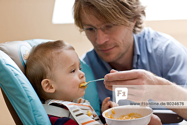 Junger Vater füttert seinen 9 Monate alten Sohn