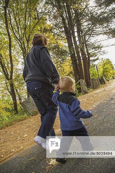 A child walks on a paved road in a park holding his grandmother's hand Willimantic connecticut united states of america