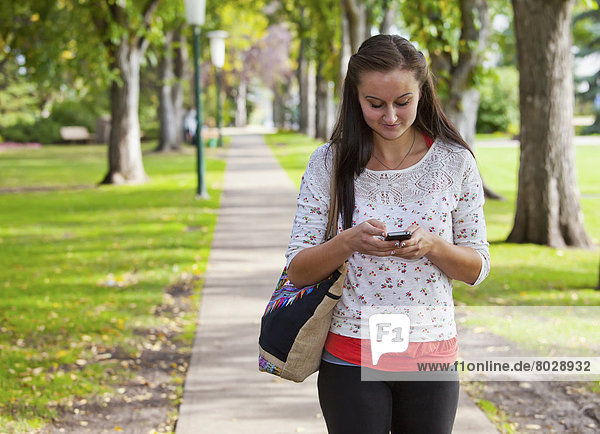 Young woman walking outdoors and texting Edmonton alberta canada