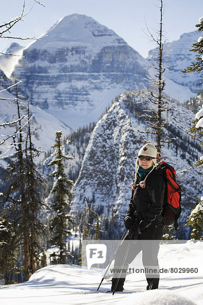 Female snowshoer in the mountains with snow covered mountains in the background Lake louise alberta canada