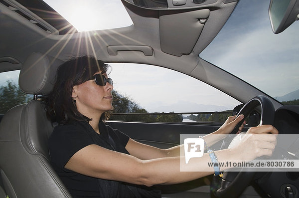 A woman driving a car with sunlight shining in the sunroof Locarno ticino switzerland
