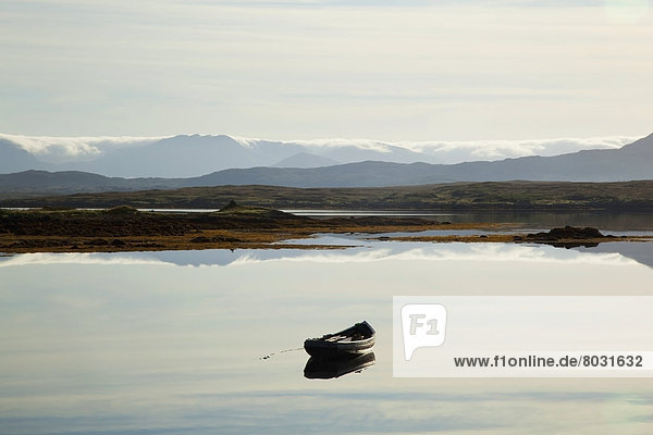 A rowboat sits in a tranquil lake with hills in the background near roundstone County galway ireland