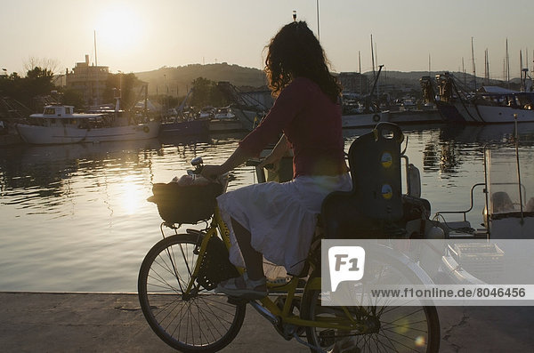 Woman on bicycle looking at sunset in fishing port  Porto San Giorgio  Marche  Italy