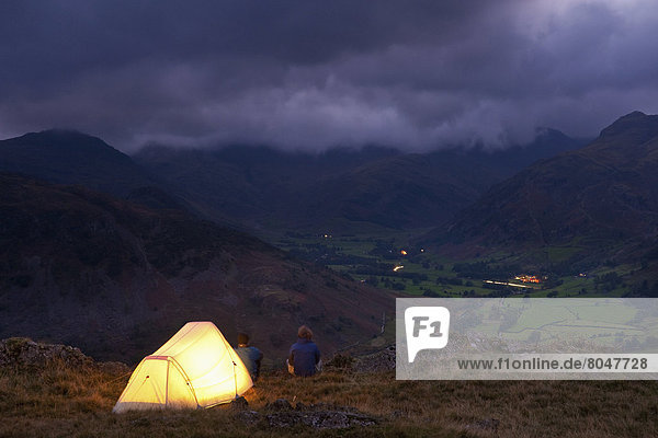 Lit tent on hill above Langdale on stormy evening  Lake District  Cumbria  England