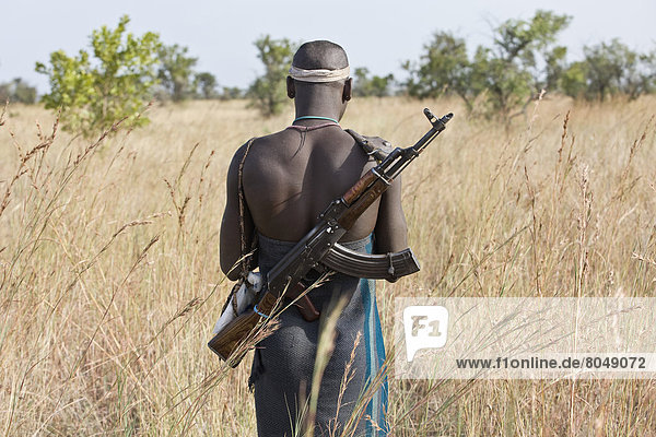 Ethiopia  Southern Nations Nationalities and Peoples' Region  South Omo  Rear view of Mursi tribal man with gun on savanah  Southern Mursiland