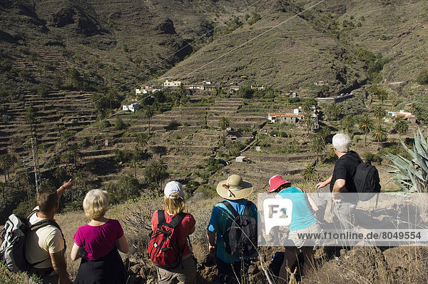 Rear view of tourists looking at Lo del Gato in Barranco de Benchijigua in Integral Nature Reserve   Santiago Ravine  La Gomera  Canary Islands  Spain