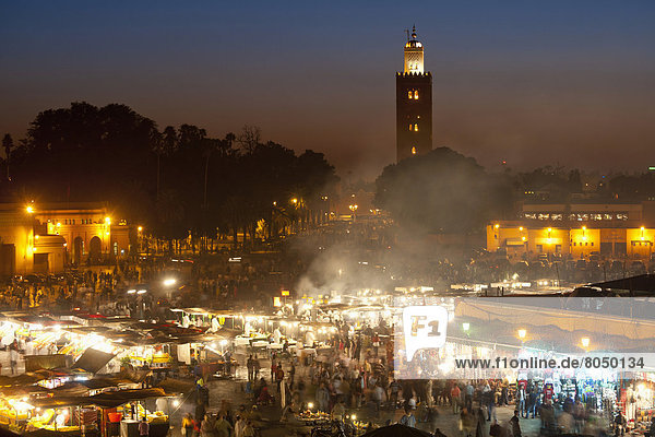 Food stalls in Djemaa El Fna with Koutoubia minaret in background at dusk  Marrakesh  Morocco