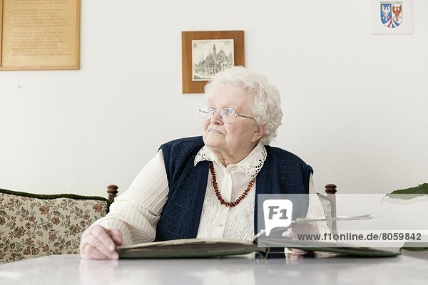 Alte Frau schaut mit einem Fotoalbum