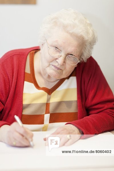 Alte Frau schreibt am Tisch