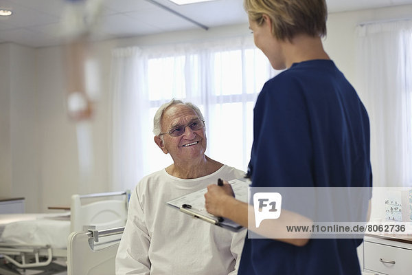 Krankenschwester im Gespräch mit älteren Patienten im Krankenhaus