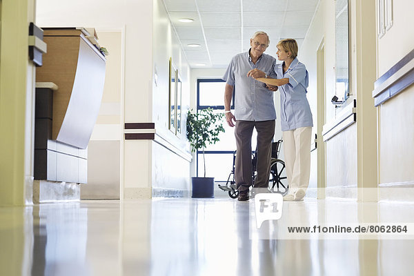 Nurse helping patient walk in hospital hallway