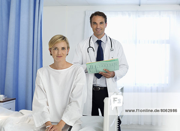 Arzt und Patient lächeln im Krankenhauszimmer
