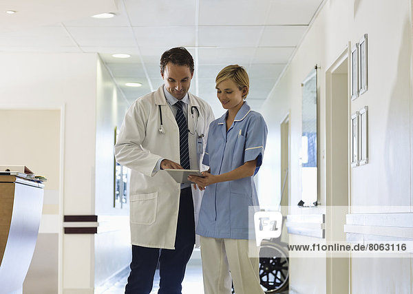Doctor and nurse using tablet computer in hospital hallway