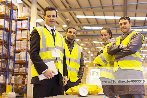 Businessman and workers smiling in warehouse