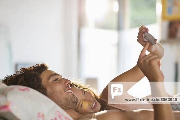 Paar mit Handy im Bett