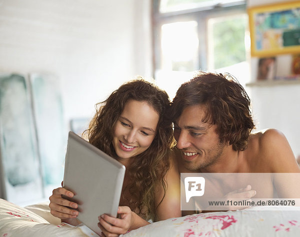 Couple using tablet computer in bed
