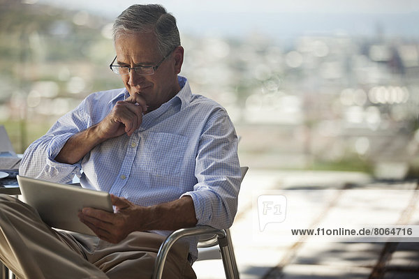 Older man using tablet computer outdoors