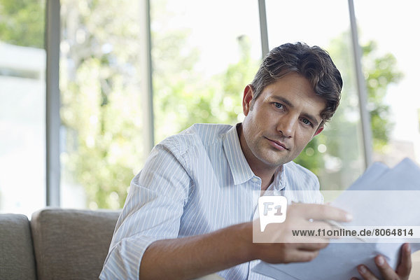 Businessman reading papers on sofa