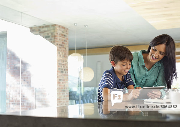 Mother and son using tablet computer in kitchen