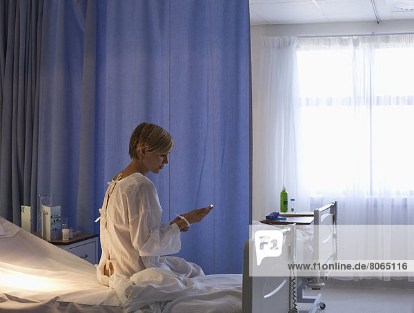 Patient mit Handy im Krankenhausbett
