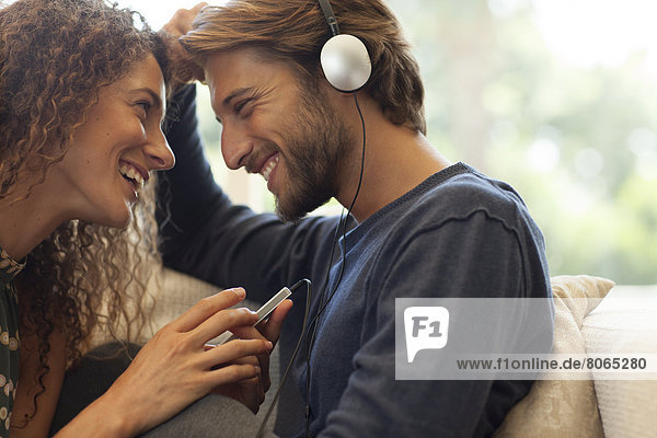 Couple listening to headphones on sofa