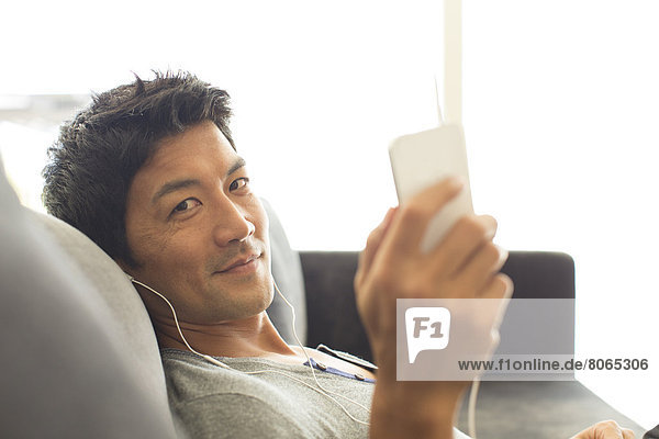 Man listening to headphones on sofa