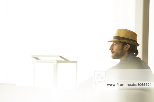 Man in straw hat looking out window