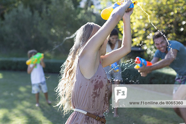 Family playing with water guns in backyard