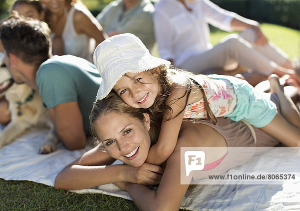 Mutter und Tochter entspannt im Gras mit der Familie