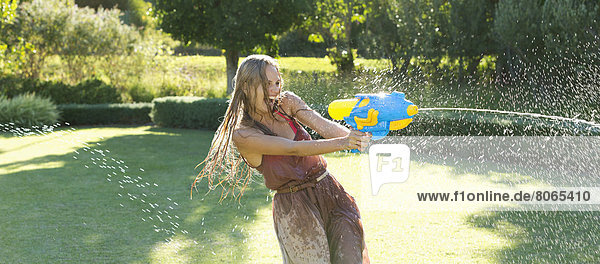 Girl playing with water gun in backyard