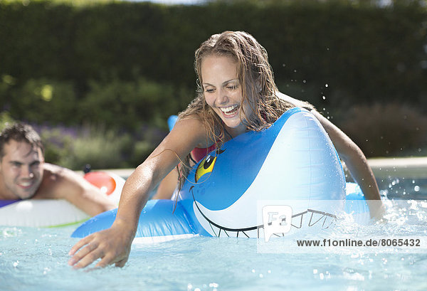 Frau spielt auf einem aufblasbaren Spielzeug im Schwimmbad