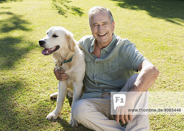 Older man hugging dog in backyard