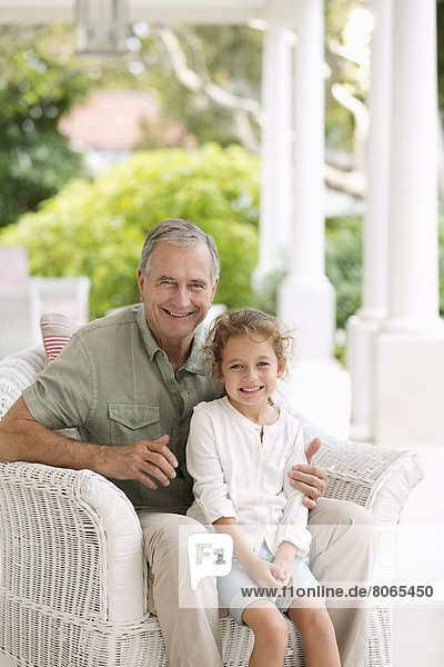 Älterer Mann mit Enkelin auf der Veranda