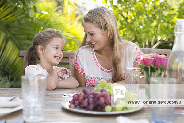 Mutter und Tochter lächeln bei Tisch im Freien