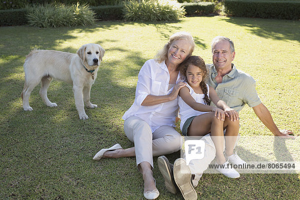 Older couple smiling with granddaughter in backyard