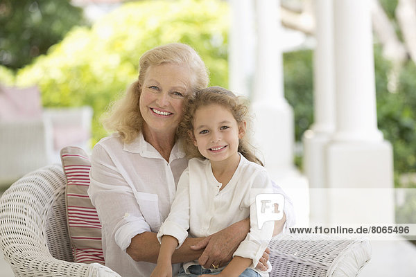Older woman and granddaughter smiling on porch