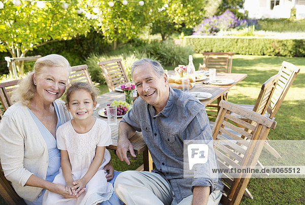 Older couple and granddaughter smiling outdoors