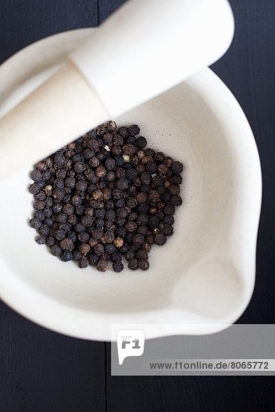 Schwarze Pfefferkörner im Mörser