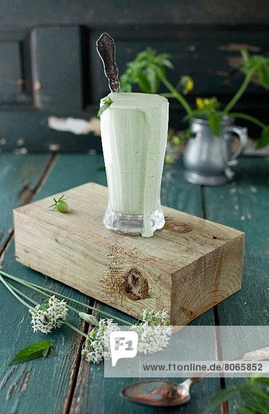 Minze-Joghurtsauce in hohem Glas auf Holzblock stehend