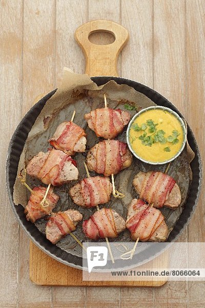Pork fillet wrapped in bacon with peanut curry sauce and corn