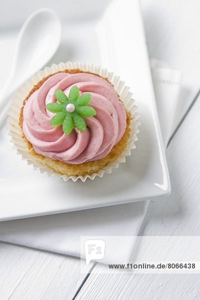Cupcake mit pinkfarbener Creme und grüner Blüte