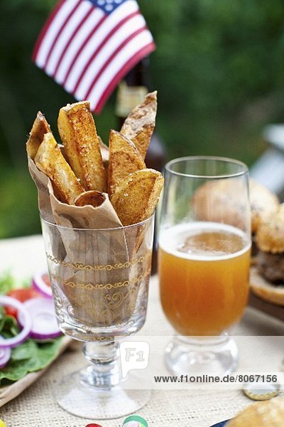 Potato Wedges auf einem Tisch im Freien  im Hintergrund büffel-Burger und US-Fahne