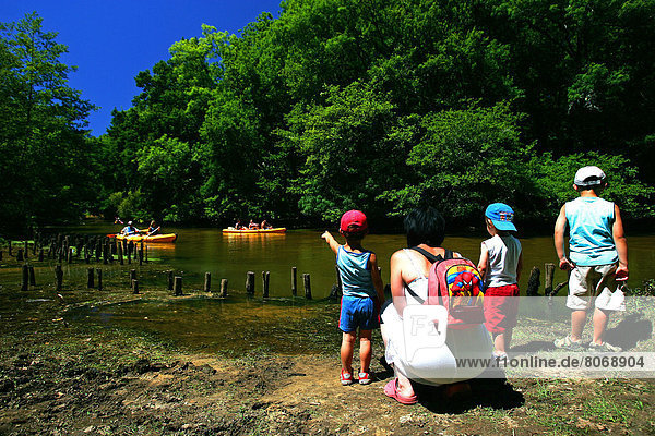Canoeing on the Leyre river : a woman and her three children looking at the canoes from the bank. River  canoe-kayak  forest