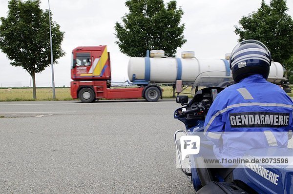 Drome department (26). 2011/06/30. Road check by the National Gendarmerie on the minor road / B road RD 532. Road safety. Motorcycle cop in the foreground  by the roadside  with red tank truck in the background