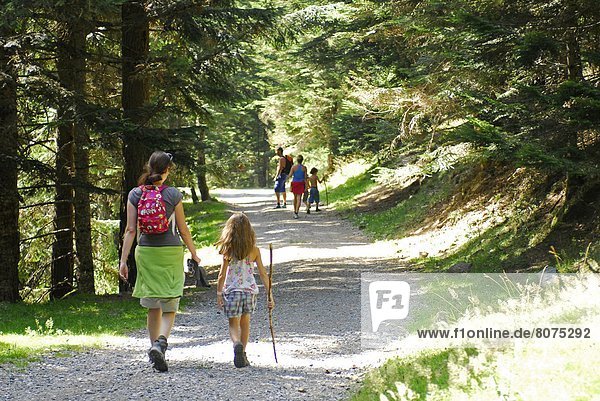 Atmosphere in a valley at Saint-Lary-Soulan in the Pyrenees (65): Family on a hike on a forest road. A woman and her daughter walking in a path in a forest