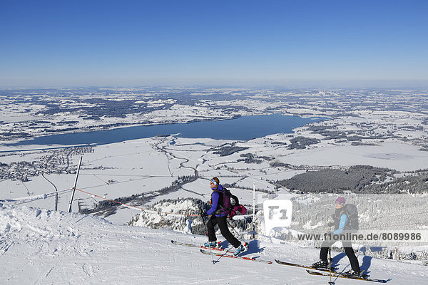 Cross-country skiers on Tegel Mountain  overlooking Forggensee lake