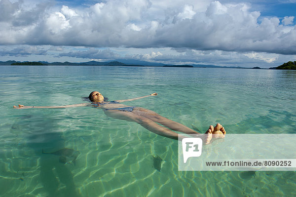 Eine Touristin lässt sich im klaren Wasser der Marovo Lagune treiben