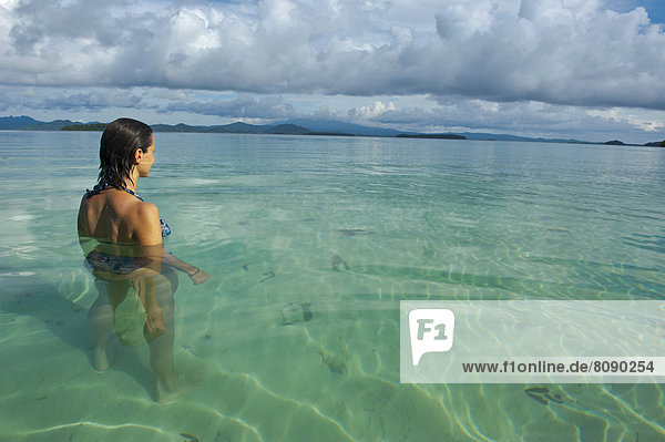 Eine Touristin steht im klaren Wasser der Marovo Lagune